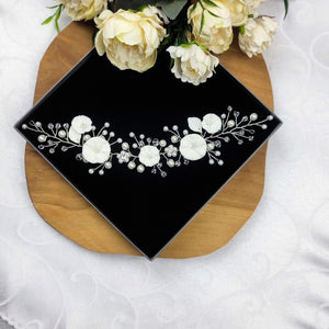 bijou de cheveux en guise de vigne de perles nacrées en verre, cristaux transparents et feuilles et fleurs blanches en porcelaine froide pour chignon ou autre coiffure de mariage