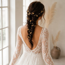 Charger l'image dans la galerie, Mariée en robe de dentelle près d'une fenêtre portant une vigne de cheveux dorée dans une longue tresse